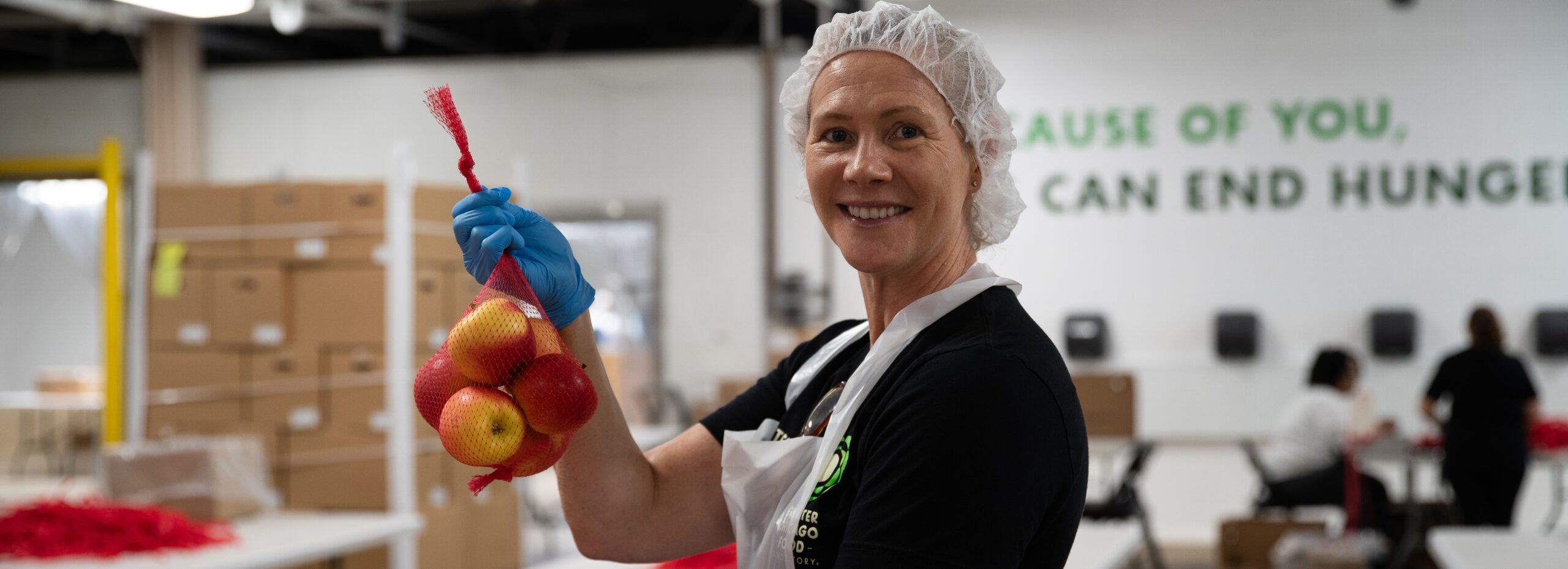 Volunteer at the Food Depository holding up a bag of apples